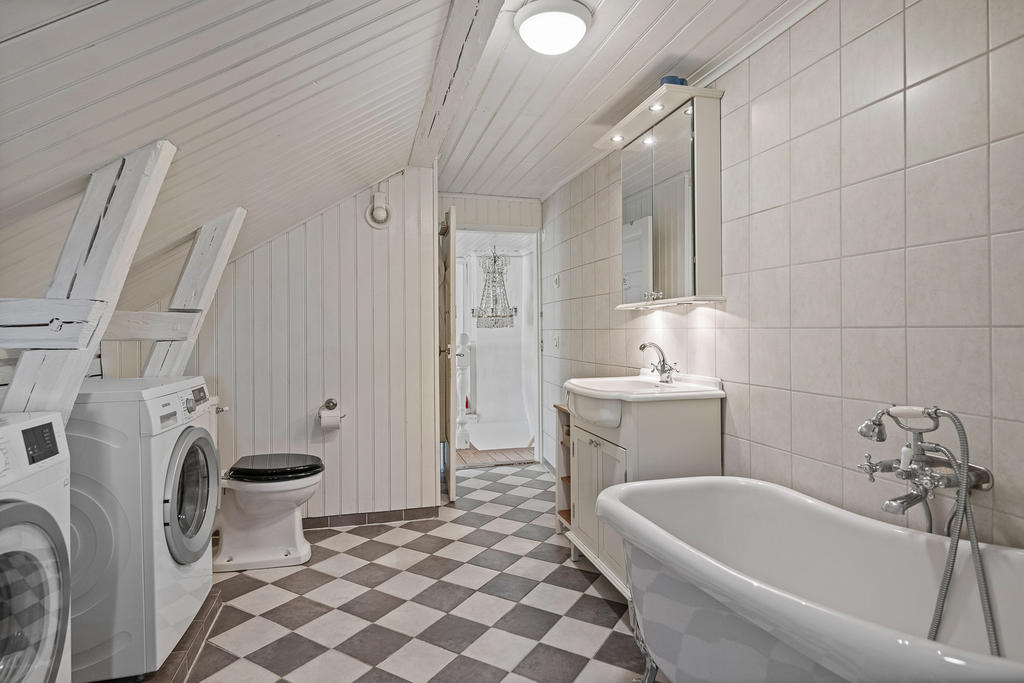 Vackert badrum med badkar, tvättmaskin, torktumlare och duschhörna