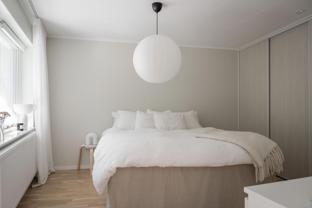 Rymligt master bedroom med inbyggd garderob med skjutdörrar utmed hela ena sidan av rummet och stora fönster mot balkongen.