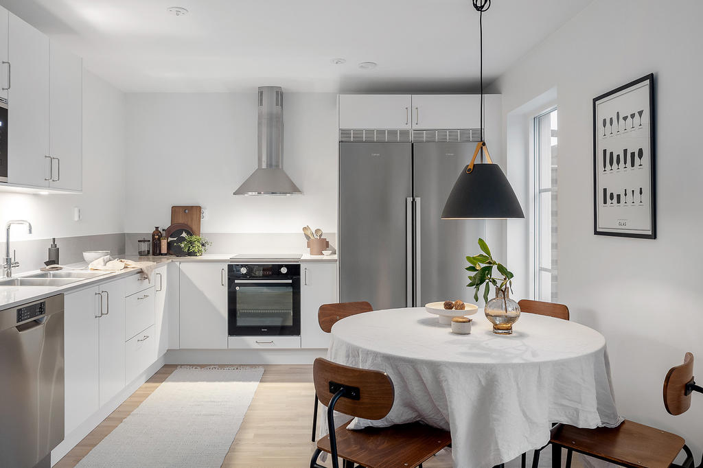 Trevligt kök i vinkel med härligt ljusinsläpp från fönster som går ända ner till golvet. Inspirationsbild från visningshuset på Nässelvägen 1A (101 kvm), notera att avvikelser förekommer gällande materialval, färger och utformning på ytskikt samt interiör i övriga bostäder.