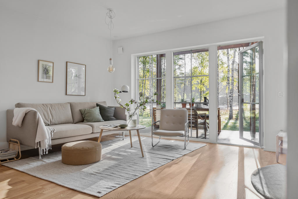 Stora fönsterpartier ner till golv i vardagsrummet ger ett härligt ljusinflöde på bostadens nedre plan. Inspirationsbild från visningshuset på Nässelvägen 6A (127 kvm).