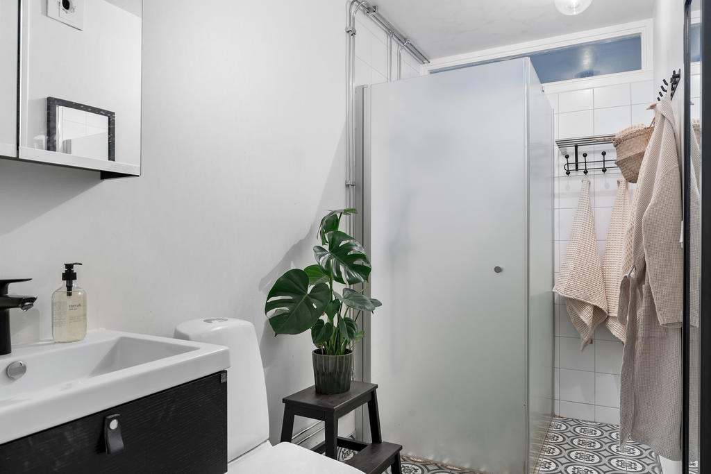 Delvis kaklat badrum med fräscht porslin och kommod. 