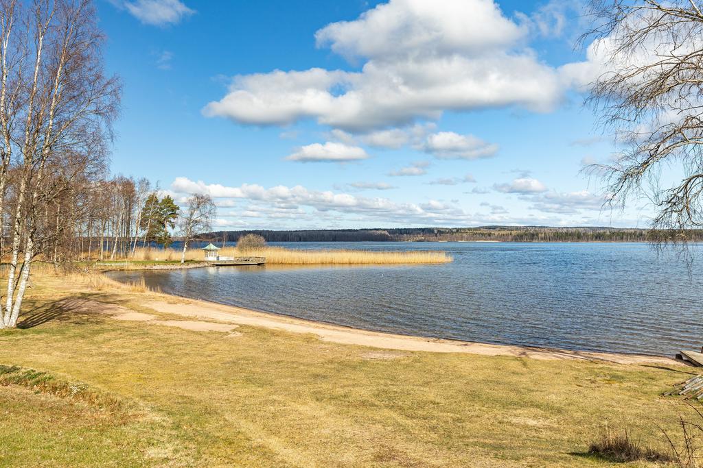 Vy över Örlenbadet med fin sandstrand , långgrunt samt hopptorn och bryggor på sommaren. 