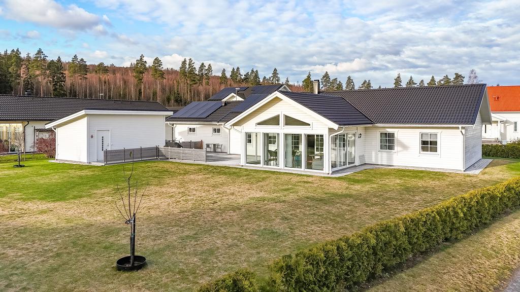 En stor baksida med inglasad altan och soldäck med en tuijahäck som växer för insynsskydd. Här finns också en varmbonad gäststuga/förråd