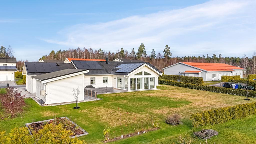 Solpaneler på taket för att sänka energikostnader. Lättskött trädgård, trädgårdsland, fruktträd och bärbuskar