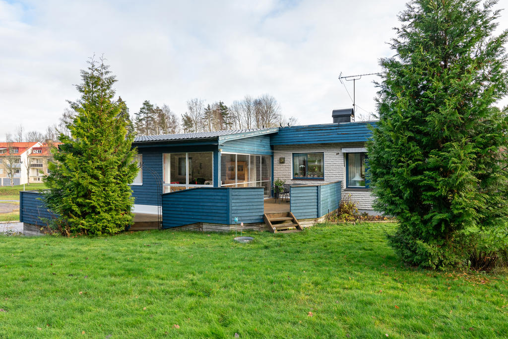 Lummig trädgårdstomt med veranda och planteringar.