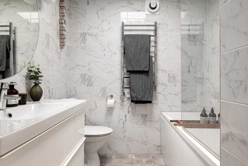 Ljust badrum med badkar och stådusch med glasvägg