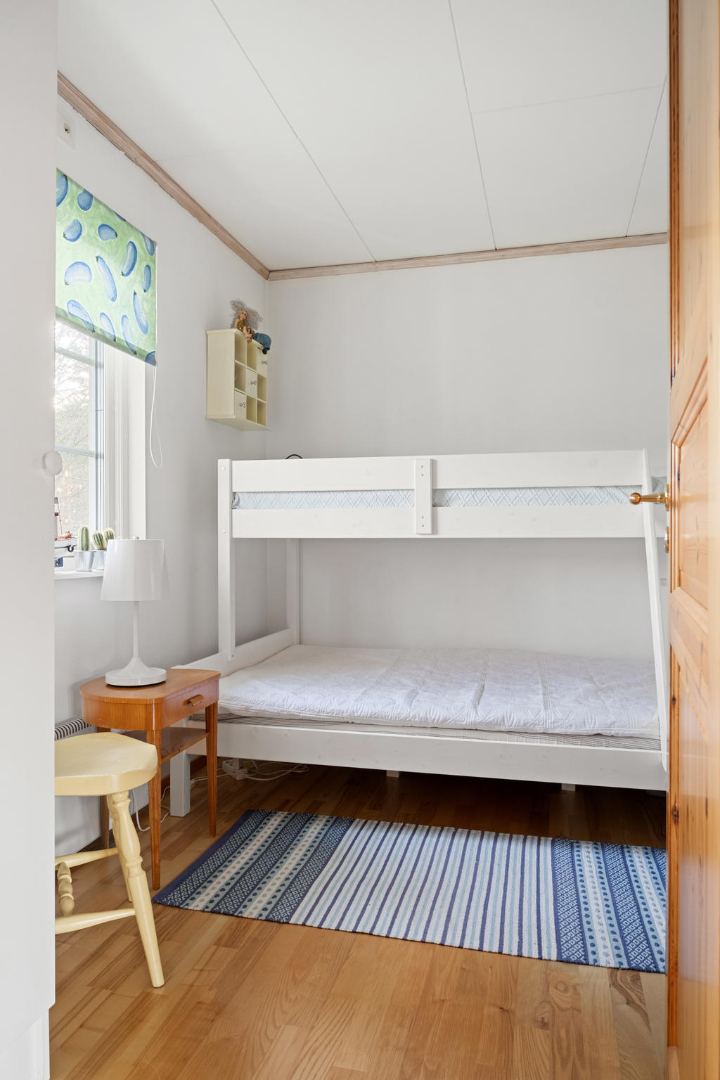 Ett ljust sovrum med generöst ljusinsläpp och smart utrymme för en våningssäng, perfekt gästrum!