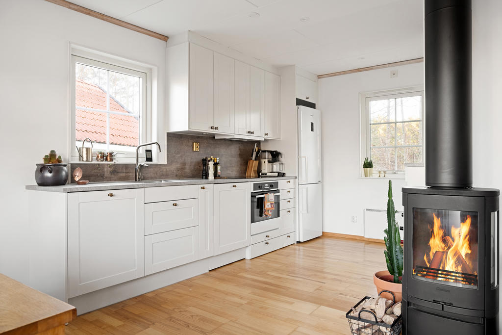 Det fräscha köket har en öppen planlösning mot vardagsrummet och är utrustat med kyl, frys, ugn, spishäll, fläkt samt diskmaskin. Det erbjuder goda arbetsytor och förvaringsmöjligheter.
