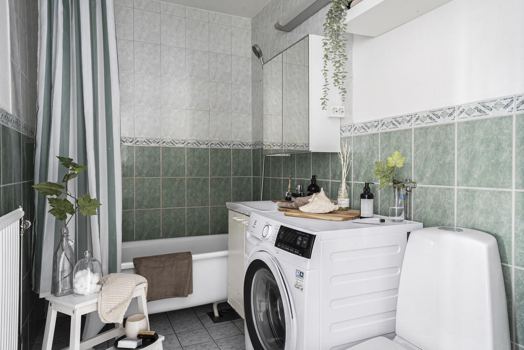 Helkaklat badrum med wc, kommod, badkar samt tvättmaskin.