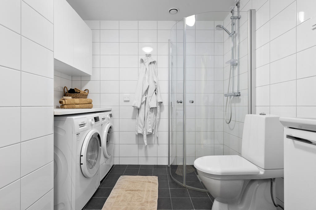 Fint badrum med generös duschplats och praktisk tvättdel 