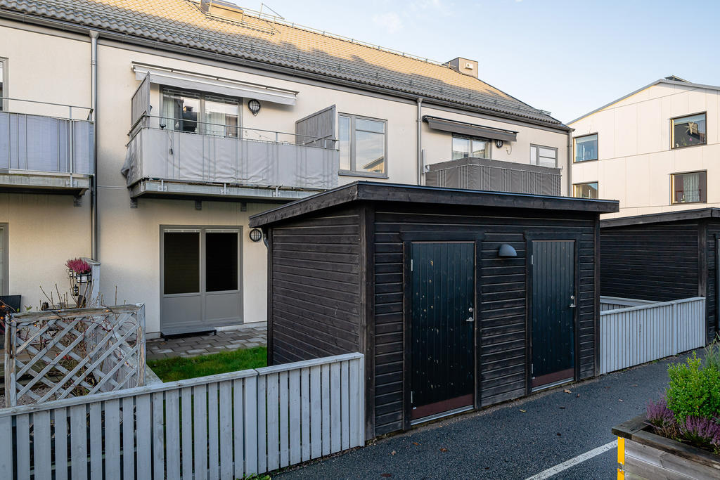 Uteplats med plattläggning, gräsmatta och förråd