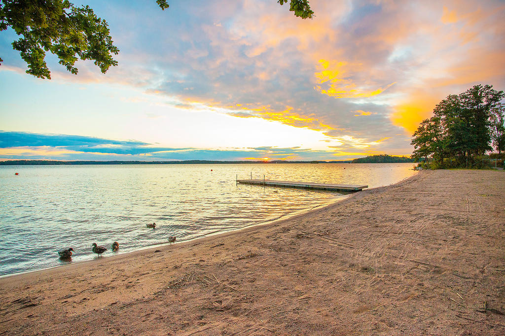 Vackra Kallhällsbadet med badbryggor, sandstrand och grönområden