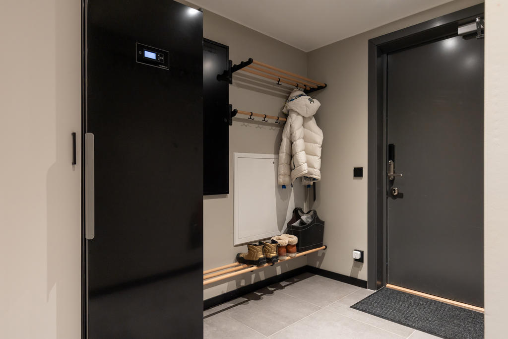 Hall med golvvärme, torkskåp och förvaringsutrymme.