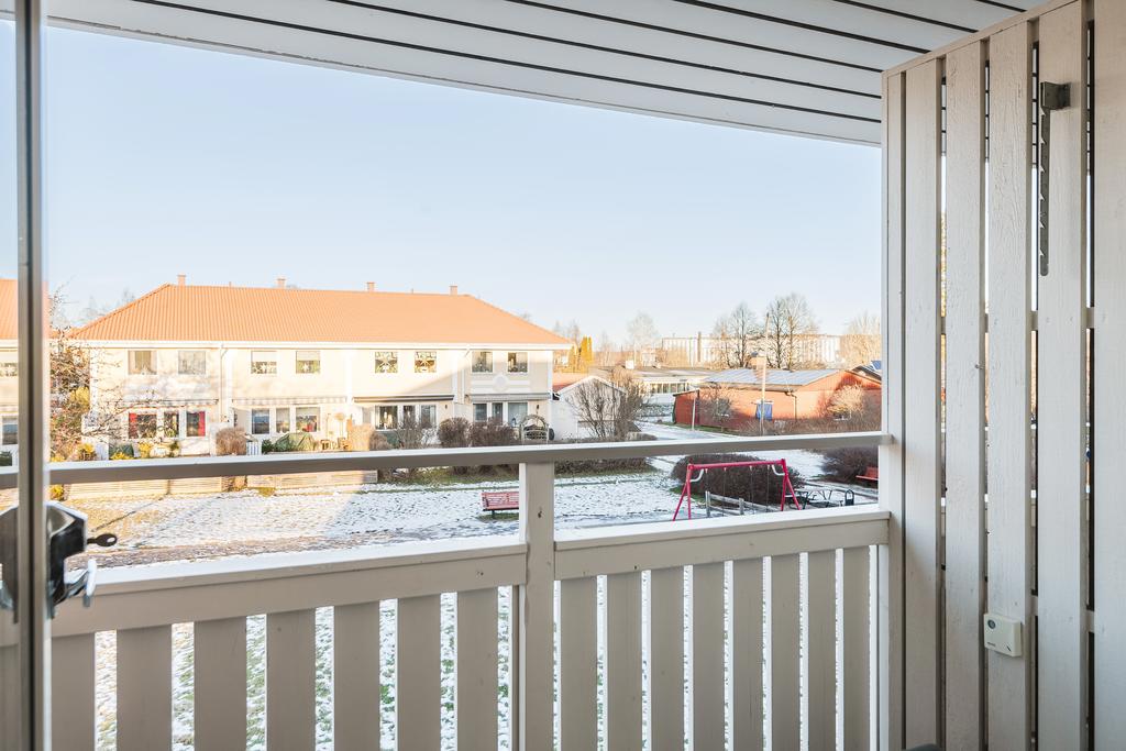 Balkong med utsikt över gården och områdets lekplats. 