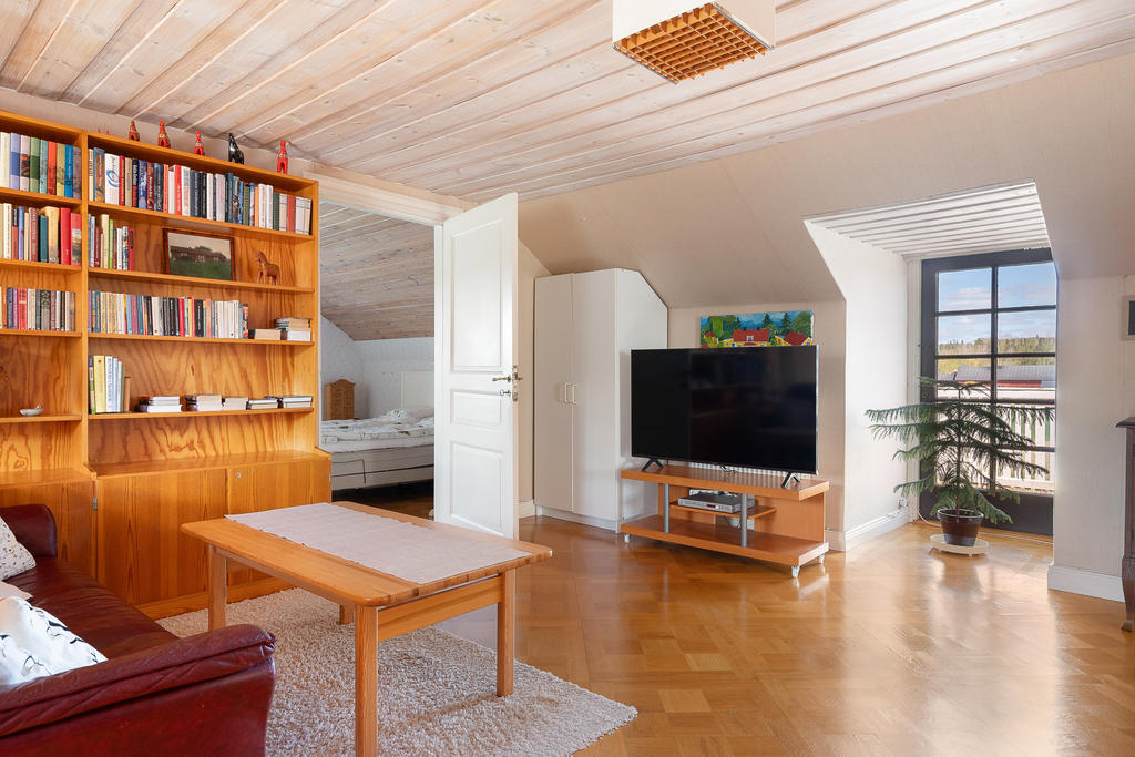 Stort allrum på övervåning med utgång till balkong på husets baksida
