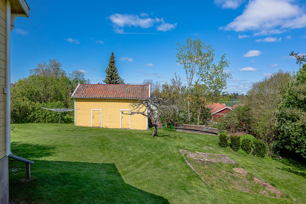 Uthus med vedbod och förråd - Sluttande trädgård på husets baksida och liten köksträdgård