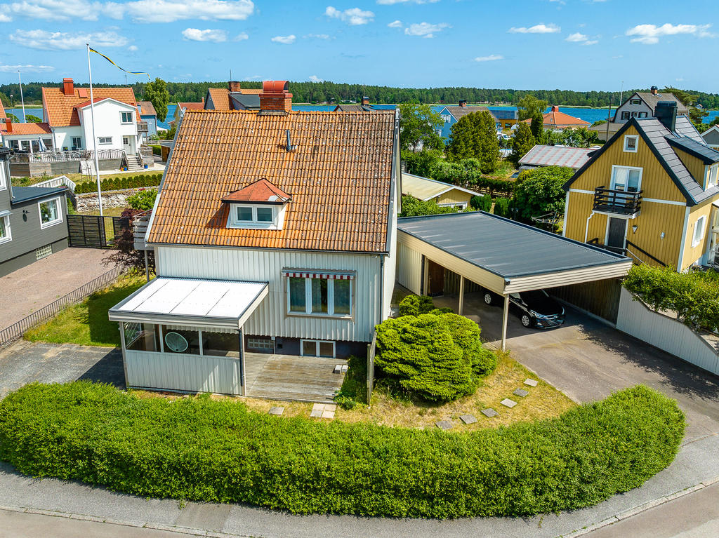 Framsida med öppen uteplats, samt uteplats under tak och carport