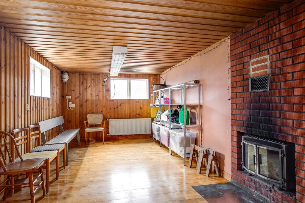 Stort sällskapsrum i källaren med öppen spis med insatskamin