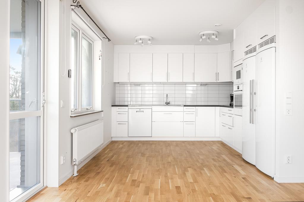Bostadens kök har inredning från Ballingslöv beståendes av vita köksluckor, mörk bänkskiva samt rostfri diskbänk.