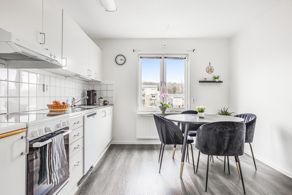 Köket har en ren och elegant design med vita skåpluckor