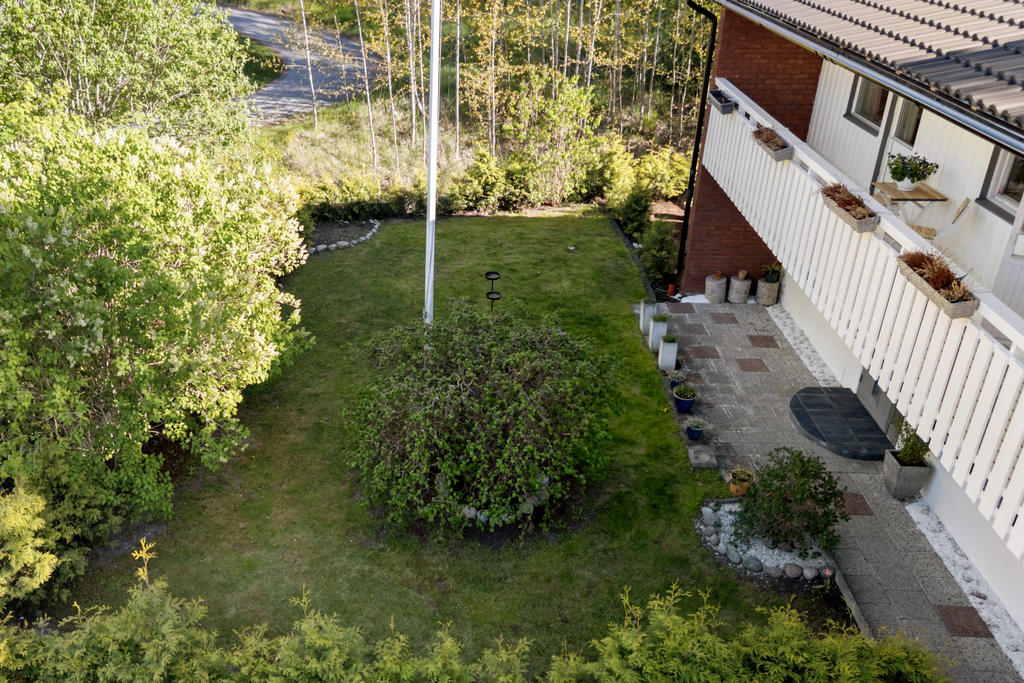 Framsida med gräsmatta, flaggstång och planteringar
