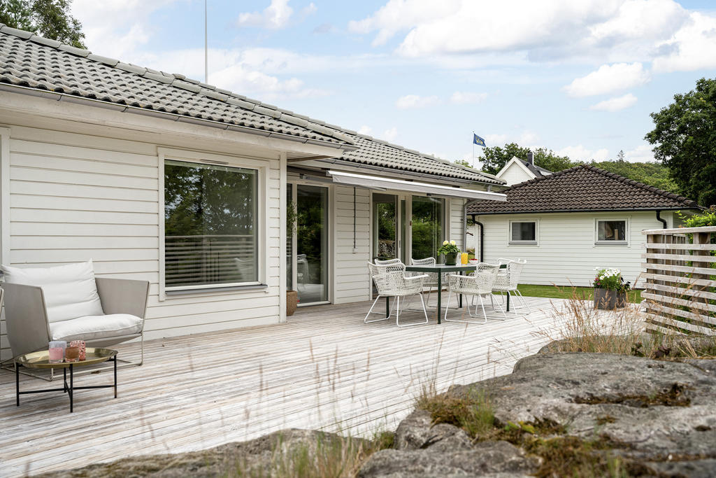 Bortanför den lättskötta gräsmattan finns en större carport med förråd