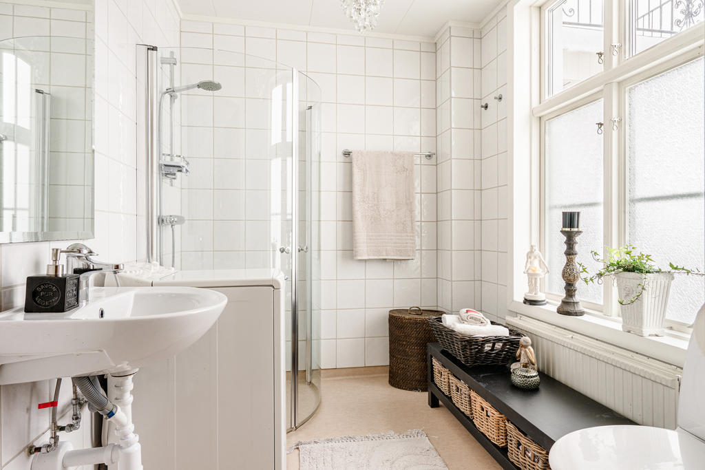 Stilrent badrum med duschkabin och toppmatad tvättmaskin.