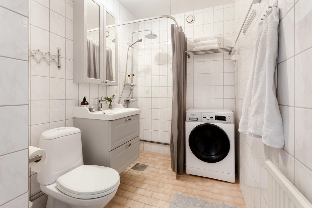 Badrum med uppdaterad inredning samt tvättmaskin med kombinerad torktumlare.