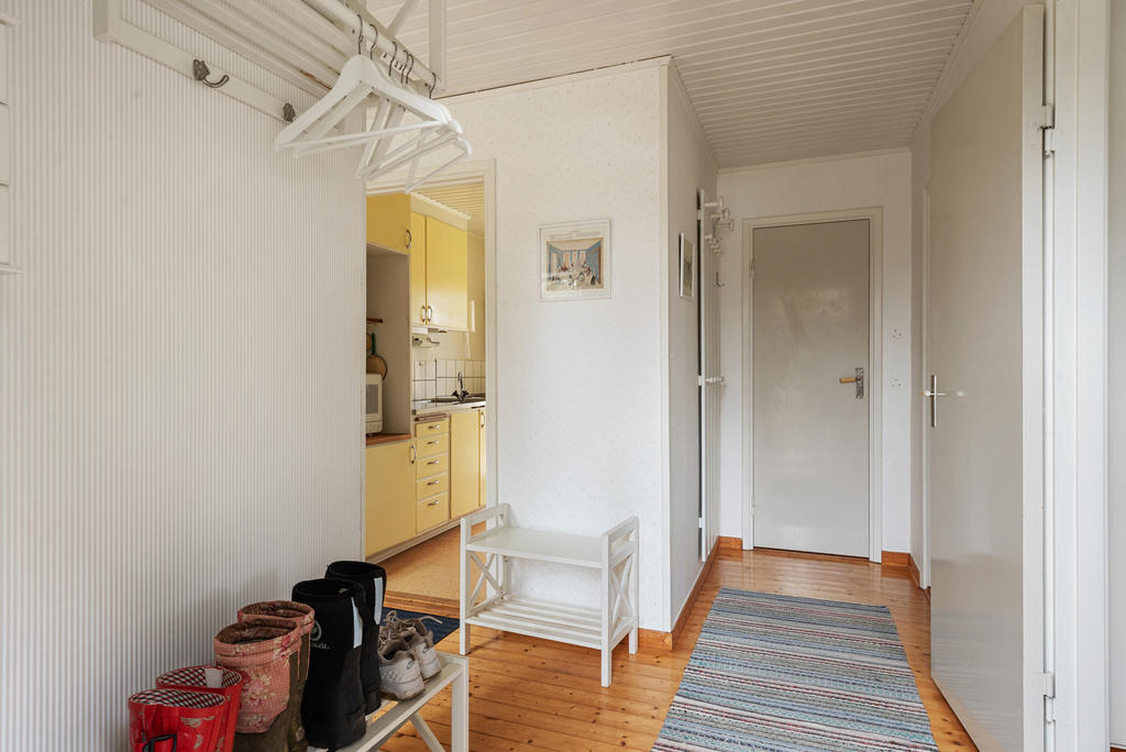 Hall med avhängningsyta direkt till vänster. Ljus och diskret randig tapet, vackert trägolv. 