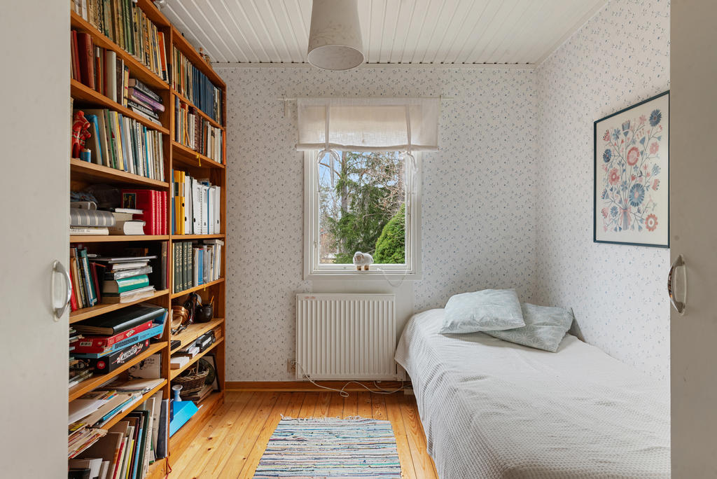 Direkt till höger i hallen finns det två sovrum. Här finns plats för sängar eller kanske skrivbord. Det första rummet har två garderober och fönster mot norr. Diskret mönstrad tapet i blått, vitt tak och det vackra trägolvet.
