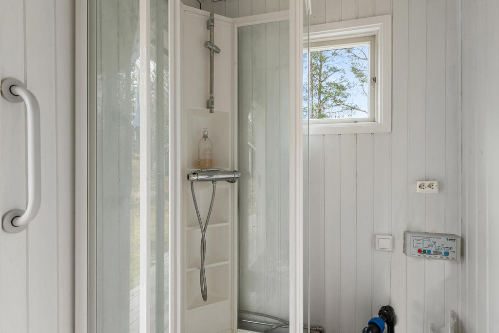 Med ingång från altanen hittar du badrummet där det finns en wc, duschkabin och handfat med kommod inunder. Även förvaringsskåp. Vit panel på väggarna och trägolv. 