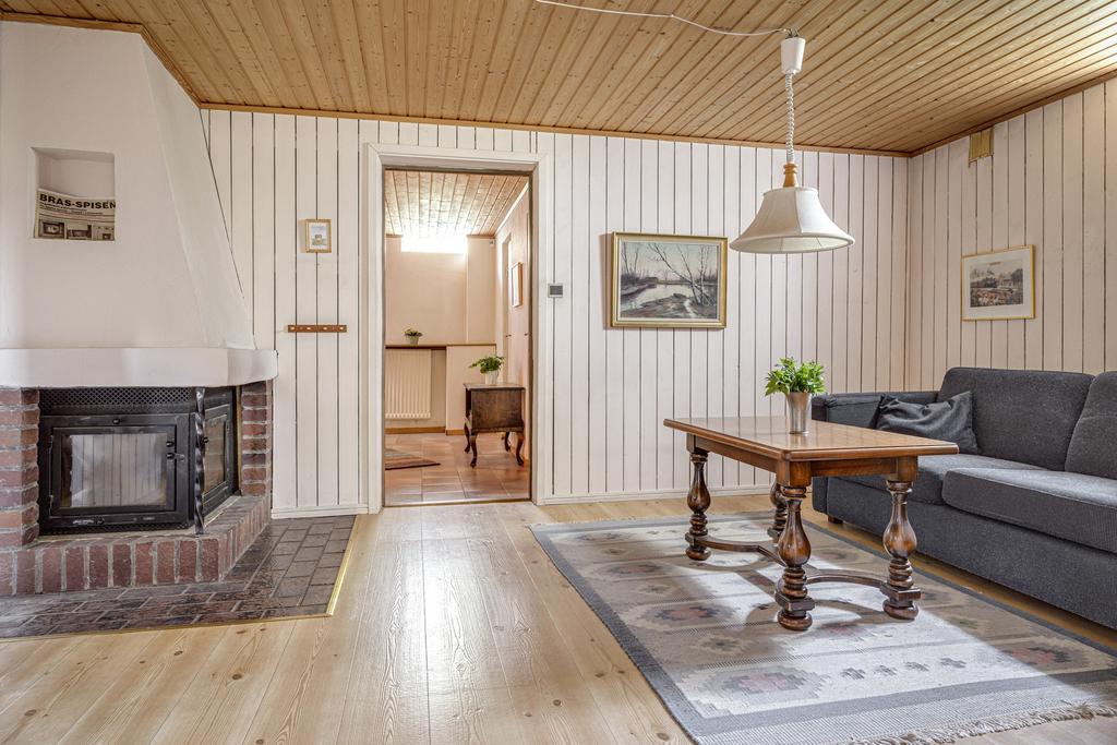 Nu har vi tagit oss en trappa ned till tv-rummet. Vit träpanel på väggarna och mysig öppen spis.