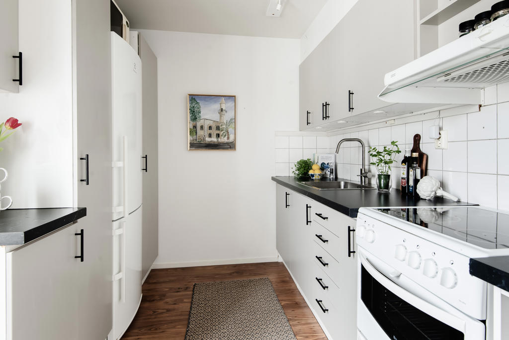 Praktiskt parallell kök med gråa släta skåpsluckor och svarta handtag 