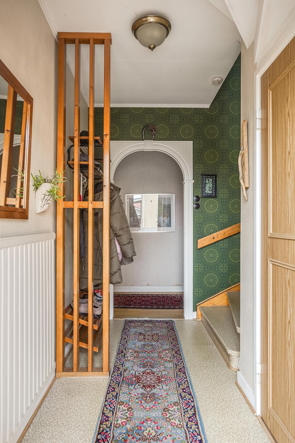 Ljus och välkomnande hall med praktisk planlösning och trappa som leder upp till övervåningen.