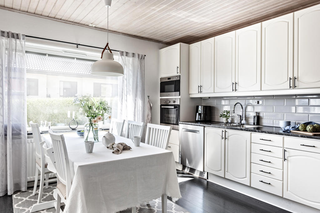 Köket är stilrent och ljust. Rymlig matplats framför fönstren och utgång till altanen
