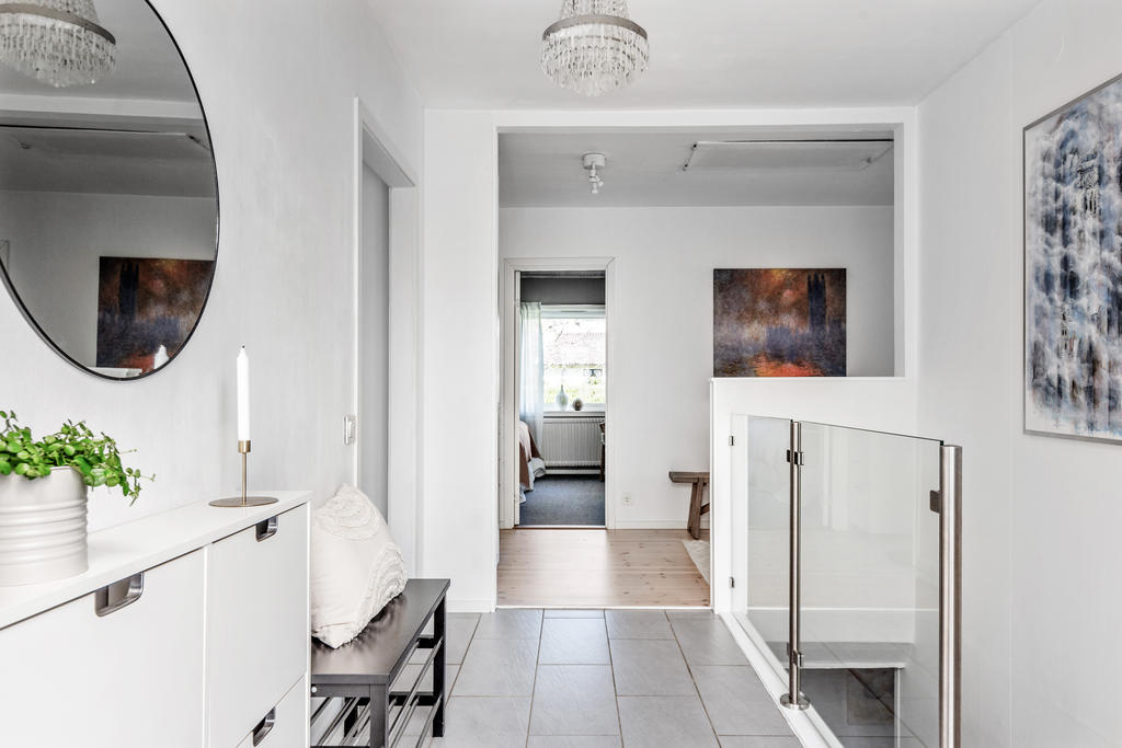 Entréhall med klinkergolv. Trappräcke i glas