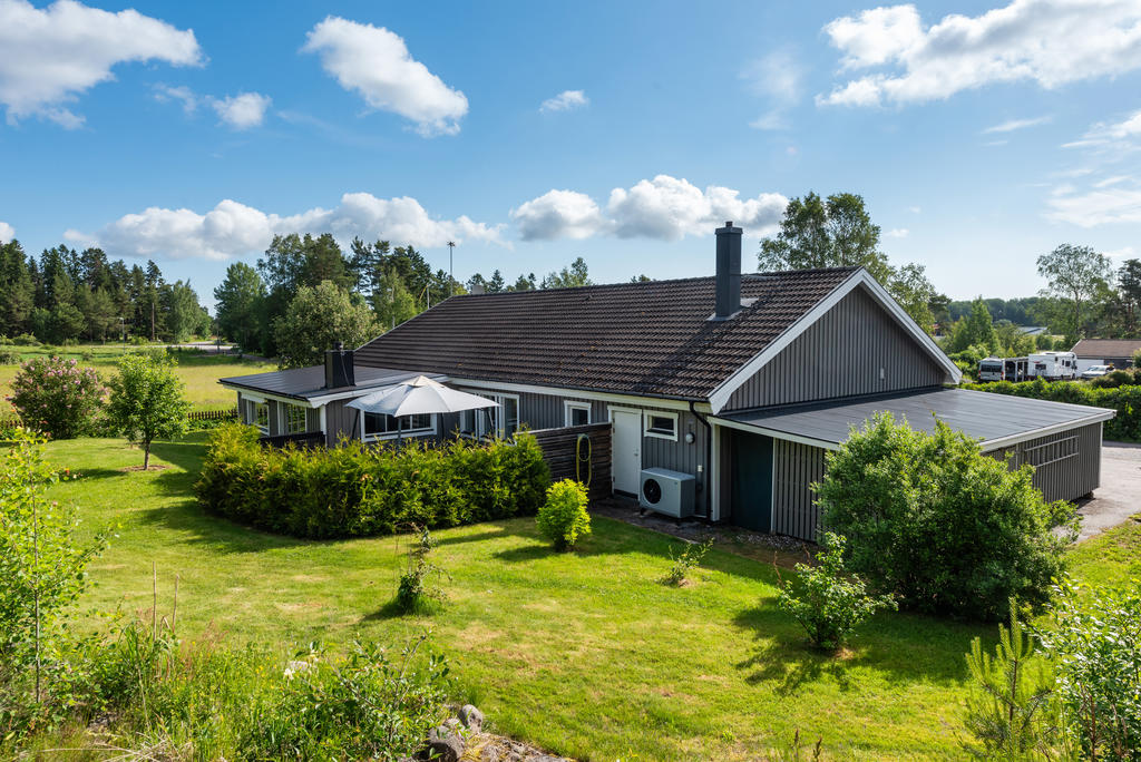 Vy över husets baksida och dess grönskade trädgård. 
