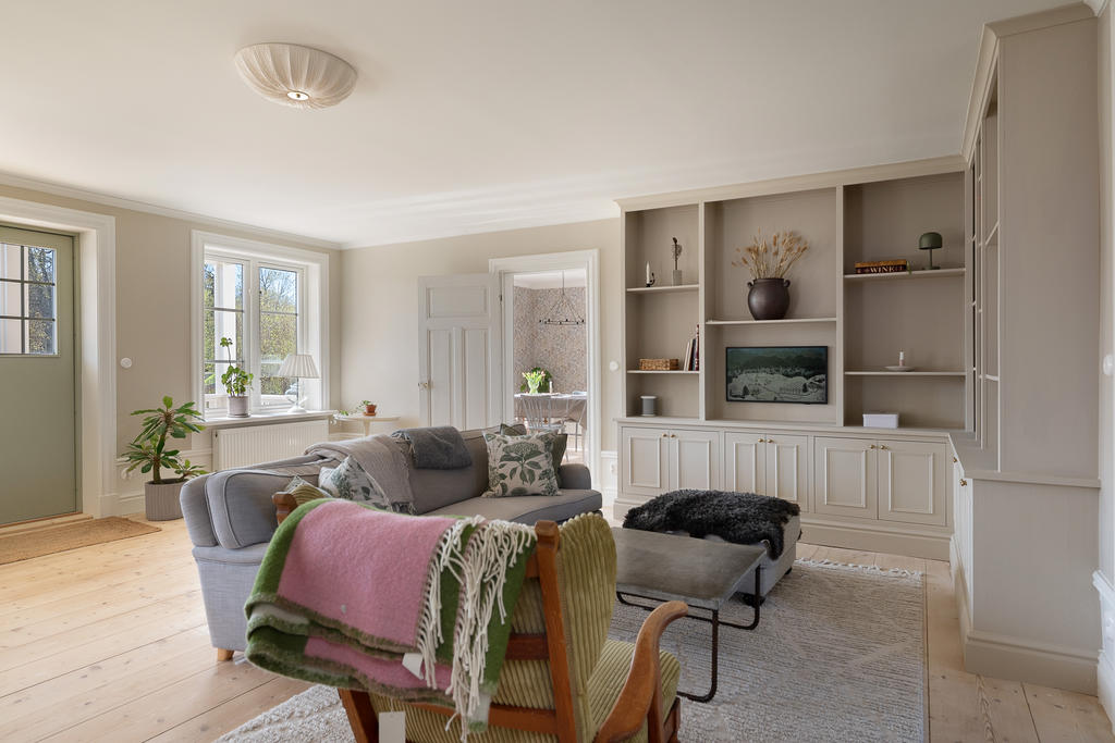 Vardagsrum med breda golvtiljor och platsbyggda skåp