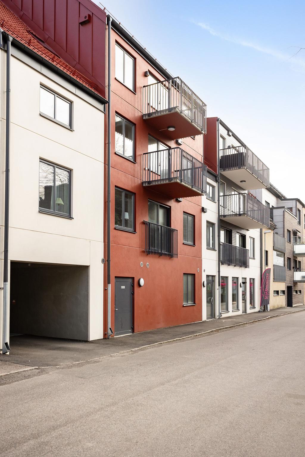 Genom husets bil passage kommer man till baksidan där garageinfarten och uteparkeringar finns 