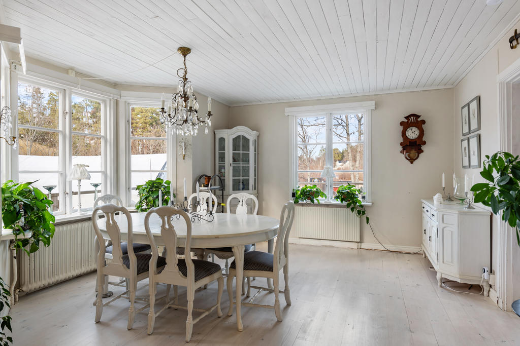Efter hallen kommer ett jättestort rum där man idag börjar med en matsalsdel med plats för många gäster. Här har huset ett vackert burspråk ut mot väster och altanen. Ljusa väggar, fönster mot norr och väster, vitpigmenterat golv och vitt tak. 