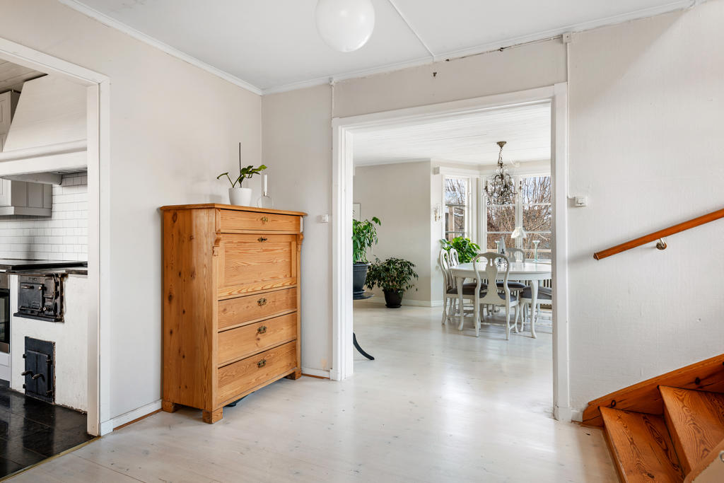 Hallen är generös med stort utrymme för ytterkläder och skor till höger vid trappan till övervåningen. Luftigt och rymligt och här finns även en gästtoalett. Ljusa väggar och ett vackert vitlaserat trägolv. 
