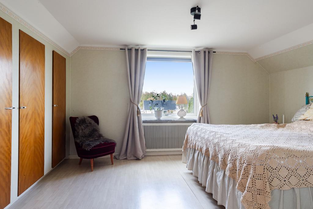 Charmigt sovrum på ovanvåningen med snedtak som ger en mysig känsla. Rummet har plats för dubbelsäng och förvaring, och ett fint fönster som släpper in ljus och ger utsikt över trädgården.