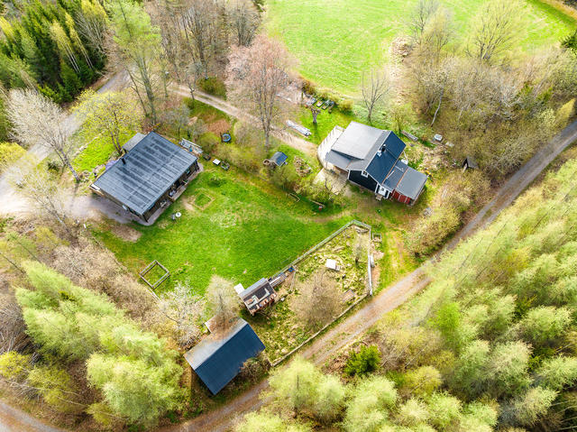 Översikt över fastigheten med bostadsbyggnad, gäststuga och uthusbyggnader