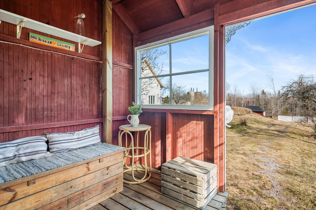 Mysig veranda under tak med plats för bänk. Här kan morgonkaffet avnjutas.
