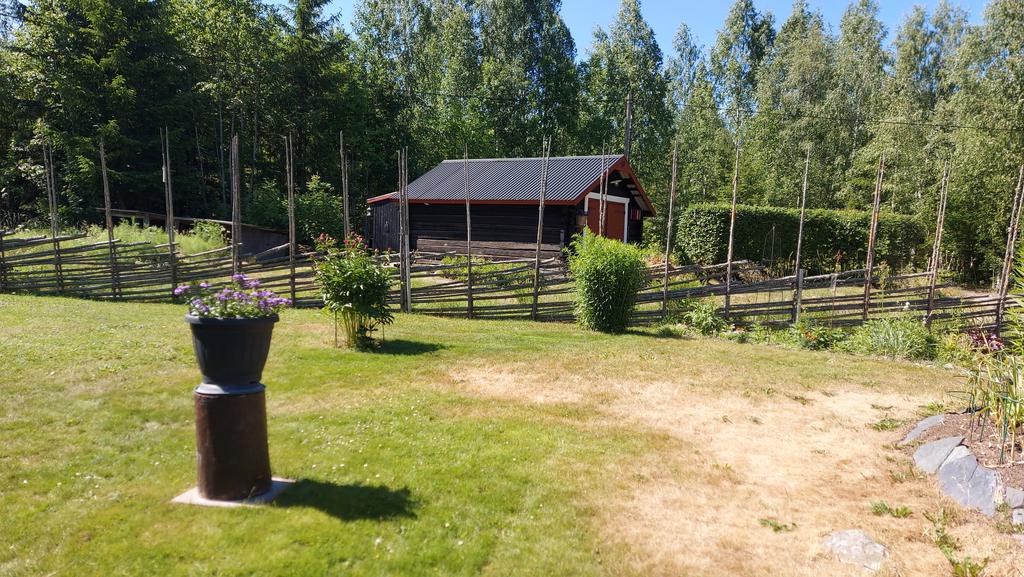 Säljarens bild över del av tomt i väster med tillhörande garagebyggnad på andra sidan staketet. 