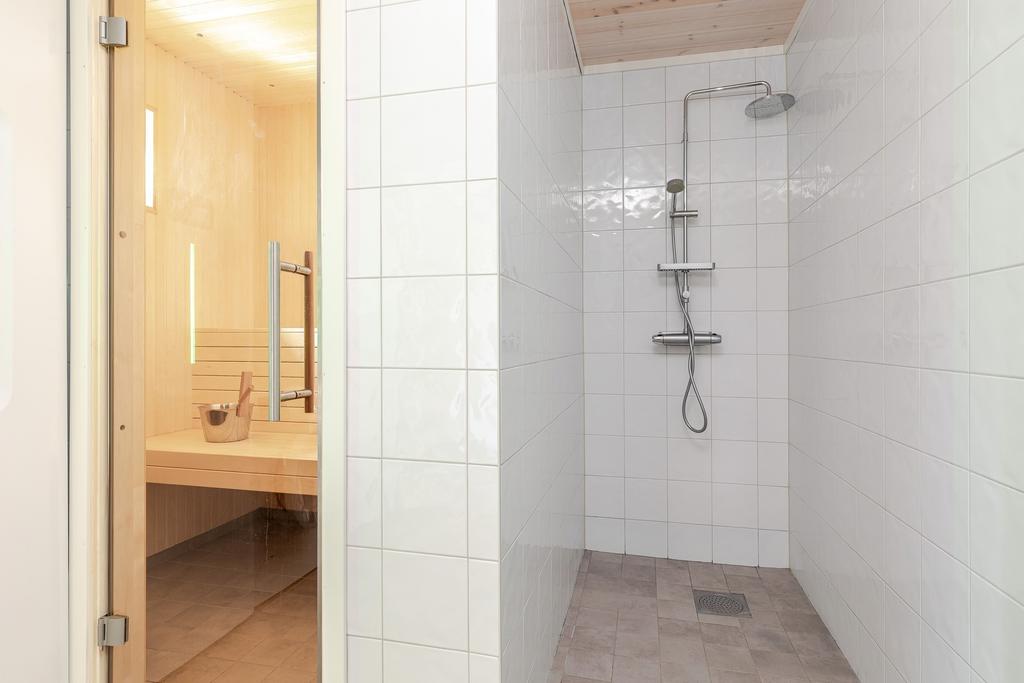 Stort badrum med wc, kommod, dusch, bastu, tvättmaskin och torkskåp.