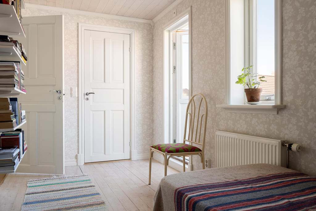 Övre plan hall med utgång till balkong i västerläge med kvällssol.