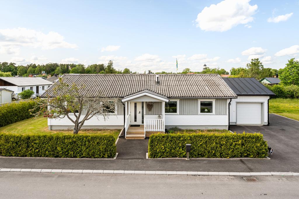 Inramad av grönskande häck och plats för ett par bilar på uppfarten