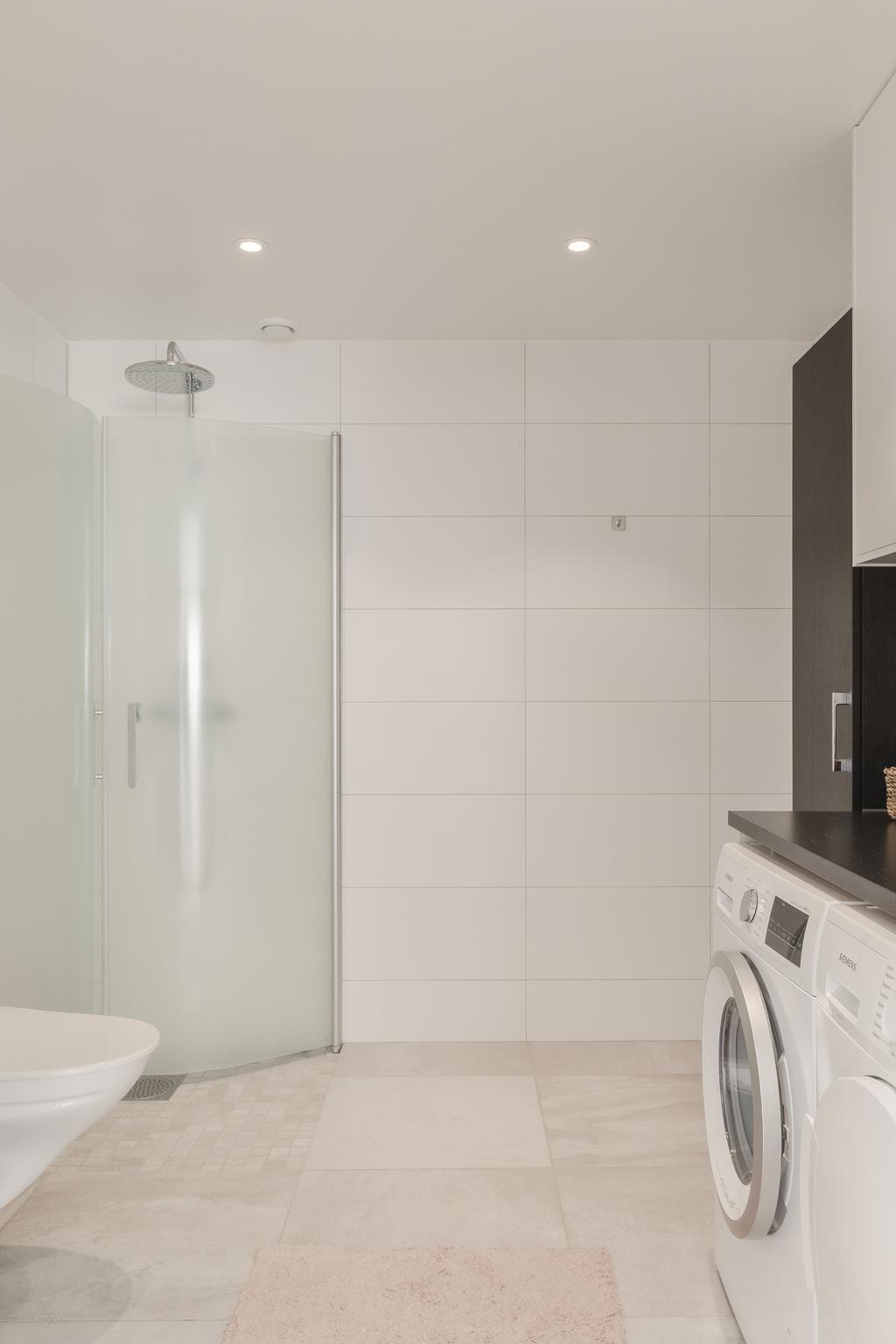 Direkt till vänster ligger ett modernt, helkaklat badrum i tidlös design.