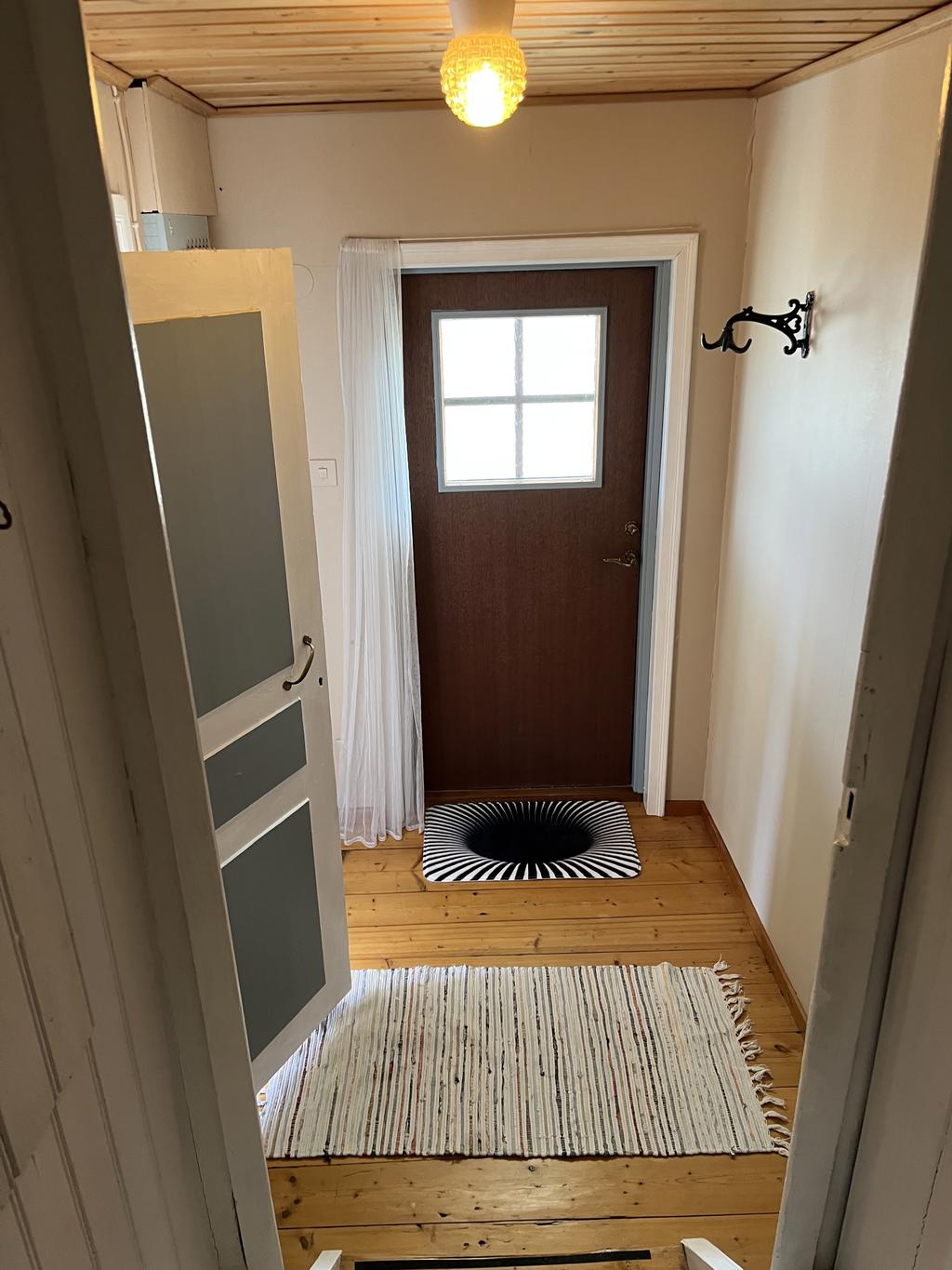 Hall med ingång från tomten och trapp upp till övervåning. 